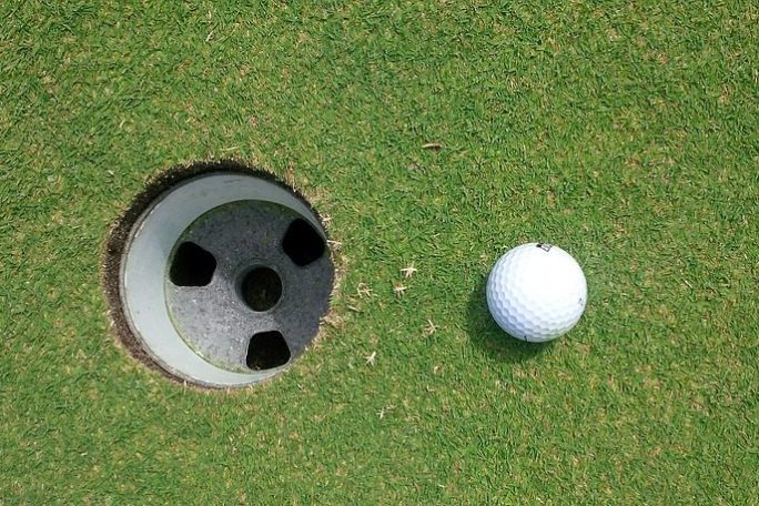 golf ball next to hole